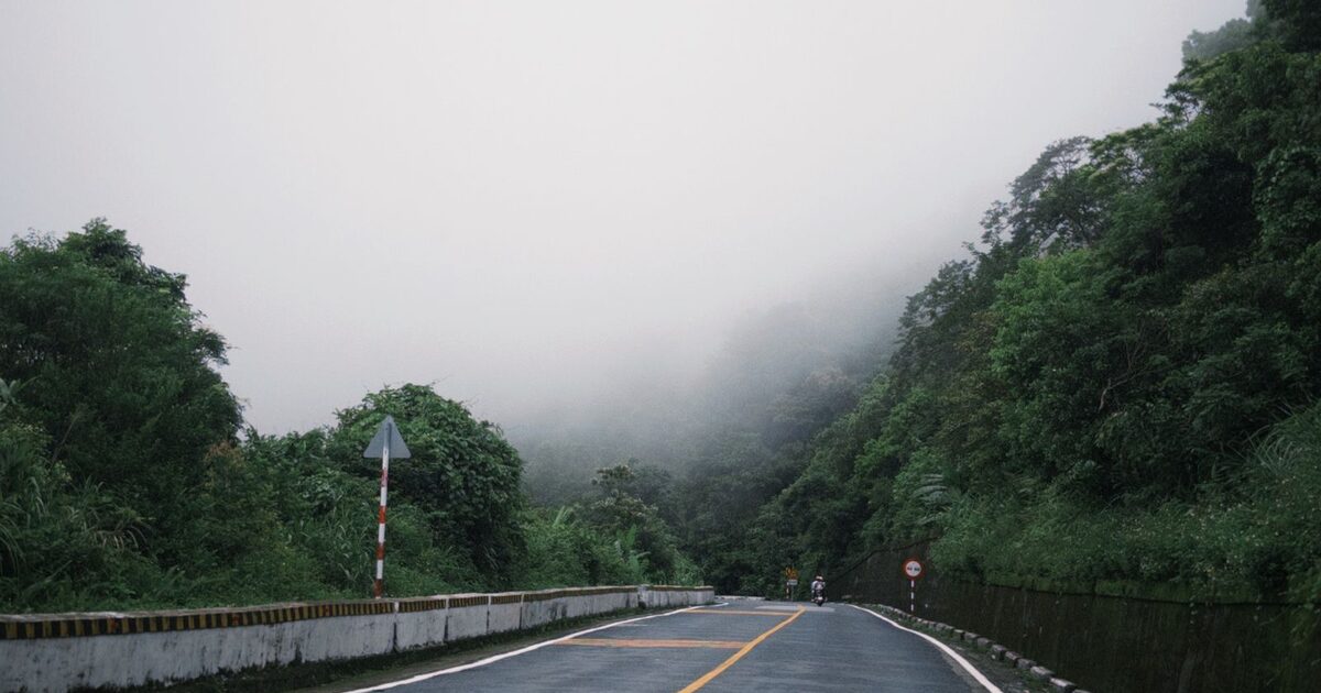 A mountain road disappearing into thick fog, a path that's there but unseen