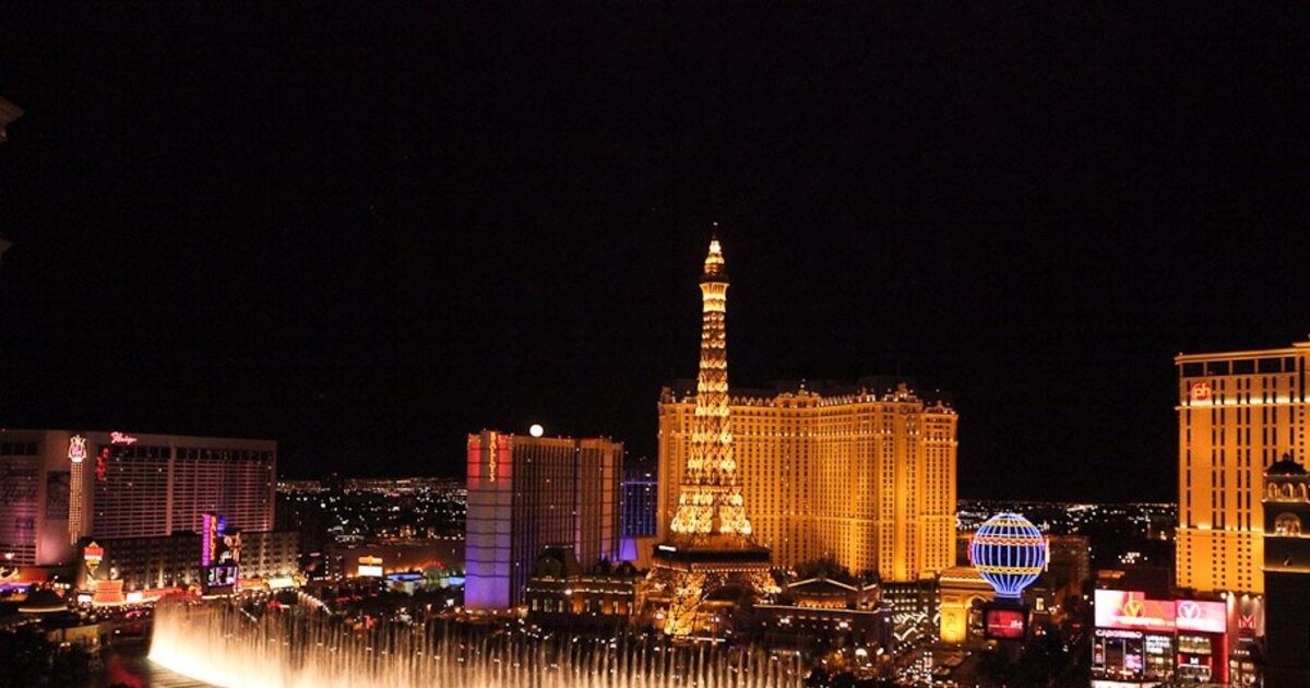 A Las Vegas neon marquee lit up against the night sky, signage either firing bright or standing dark