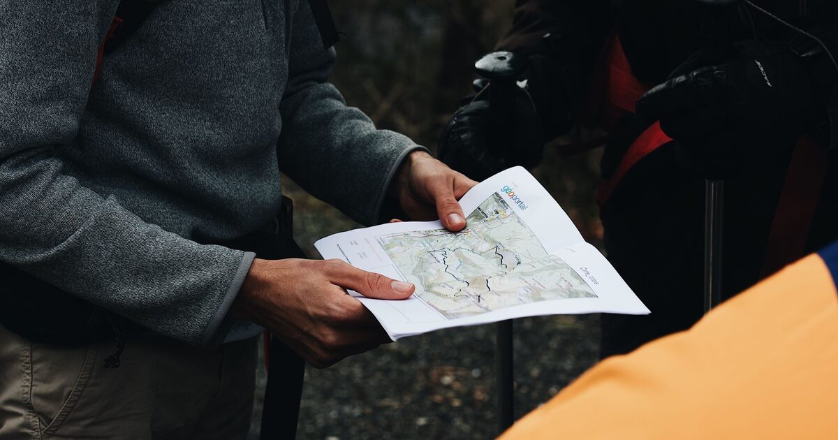 A traveler holding a paper map open in both hands, working out the route ahead